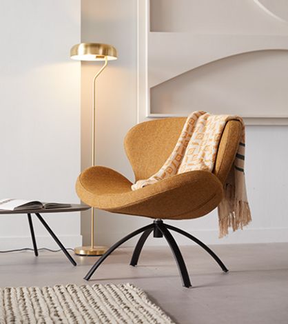 Oranje fauteuil met een plaid en een gouden sfeerlamp